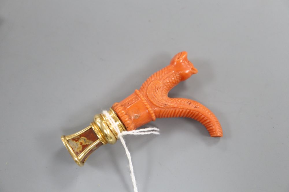 An early 20th century cased yellow metal mounted jasper seal with coral handle carved as a dragon (tail broken)